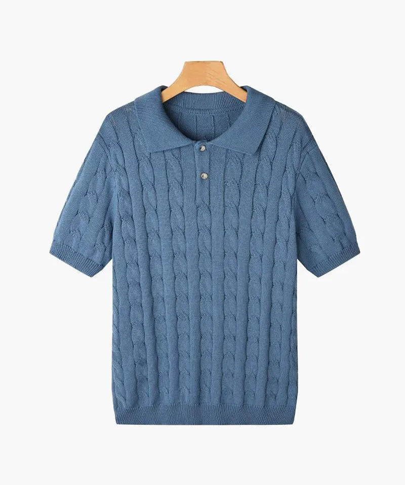 Blue cable knit sweater on a hanger against a white background