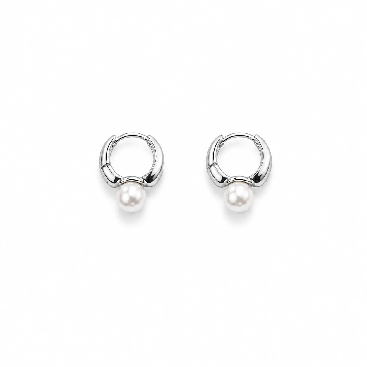 A pair of silver huggie hoop earrings with a small white pearl dangling from the bottom, shown on a clean white background.