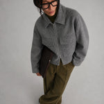 women is earing a Short Tweed Coat in grey with green trousers, black shoes and glases