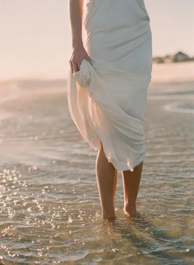 FERNACHE flowing beige dress by the shore – timeless Old Money summer fashion captured in soft natural light.