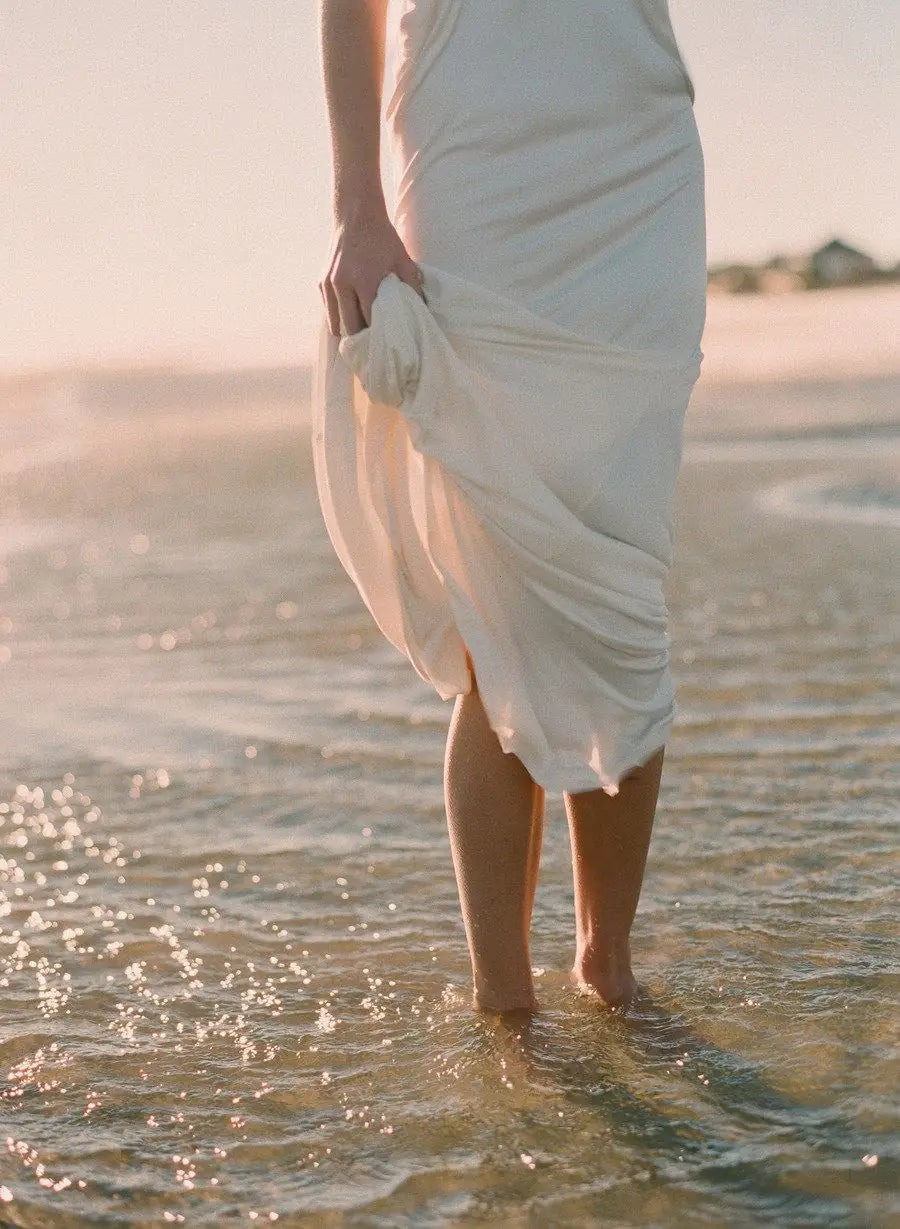 FERNACHE flowing beige dress by the shore – timeless Old Money summer fashion captured in soft natural light.